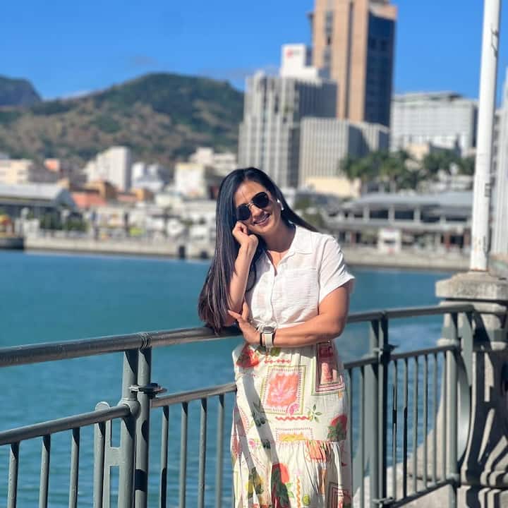 In this look, the look looks natural with a simple white shirt with multicolor printed long skirts sunglasses and simple hair.