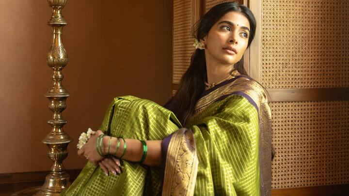 Pooja went for traditional timelessness draped in this green Kanjeevaram saree with gold checkered fabric. A purple blouse with gold trimming and subtle accessories completed the heritage look. (Image Source: Instagram/ hegdepooja)