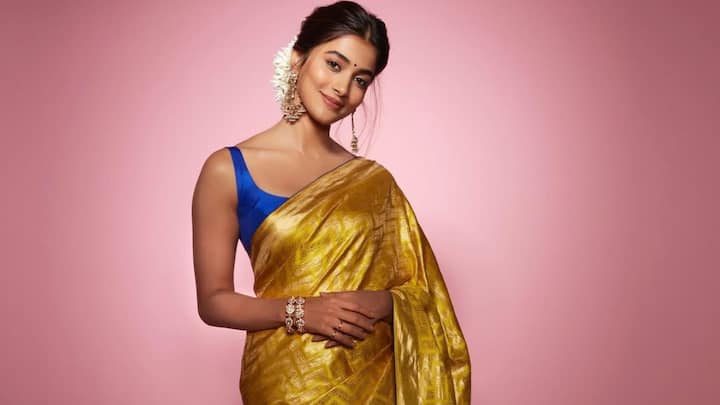 In this mustard-coloured saree with a natural shine, and paired with a contrasting royal blue blouse, she presented a bold festive appearance. Classic earrings and a gajra bun complemented the festive-ready look. (Image Source: Instagram/ hegdepooja)