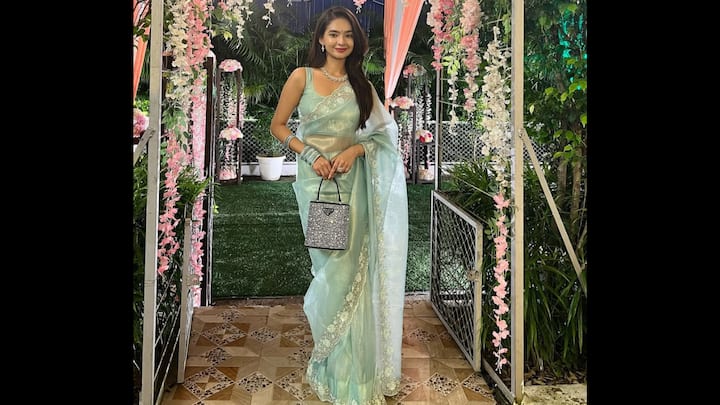 1. Pastel Sheer Saree: This pastel sheer saree is the ultimate Raksha Bandhan 2025 inspiration. The delicate fabric, enhanced with an embroidered lace border gave the actress a dreamy and ethereal look. She paired her saree with a sleeveless blouse, statement handbag, and matching jewellery. This soft pastel shade offers sophistication without being overpowering. This airy fabric with subtle tones and statement jewellery, served as the right mix of glamour and grace. (Image Source: Instagram/@anushkasen0408)