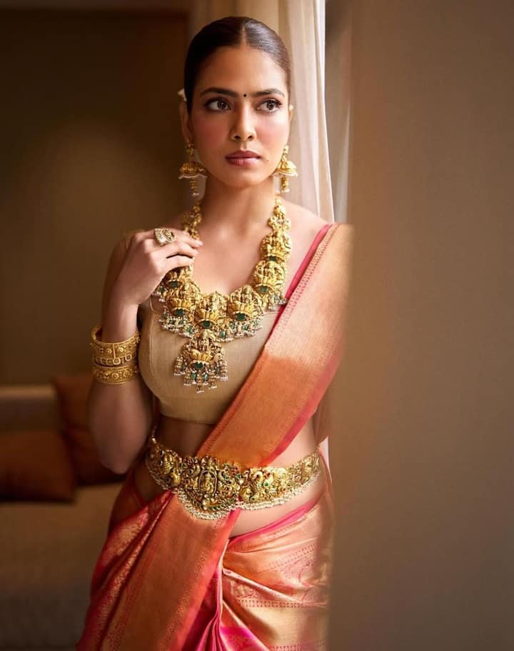Traditional South Indian Glam: She channeled a South Indian bridal dream in a rich orange and crimson Kanjivaram saree with intricate Vanasingharam designs. Emerald-studded gold jewelry, bangles, rings, and a kamarbandh made her look nothing short of regal.