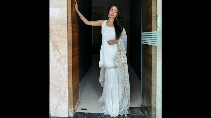 6. White Sharara Set With Gold Accents: Anushka Sen’s all-white Sharara set is the definition of elegance and grace. The sleeveless kurti paired with a flared Sharara and a dotted dupatta with scalloped golden borders gave the fit a dreamy and festive vibe. The actress completed her look with a matching potli bag and accessories. This styling proved that less is more when done right. (Image Source: Instagram/@anushkasen0408)