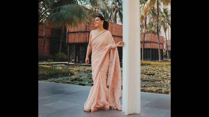 2. ⁠Soft Blush Minimal Saree: Kajol stunned in a blush pink saree that perfectly captures the essence of simplicity and grace. This minimal saree is the ideal choice for Raksha Bandhan 2025 celebrations. The pastel pink drape adorned with delicate embroidered along the borders created a soft and feminine silhouette. Paired with a matching sleeveless blouse and styled with classic statement earrings, Kajol’s saree screamed modern minimalism. For all those who are seeking understated elegance, this saree with soothing hue and subtle shimmer is a great pick. (Image Source: Instagram/@kajol)