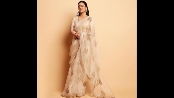 6. ⁠Ethereal Timeless Drape: Kajol showcased a breathtaking ensemble that is perfect for the festive season. This outfit is a statement of grace and timeless beauty. Kajol’s outfit featured a pristine organza saree. The sheer drape was embellished with intricate golden embroidery that created a subtle yet luxurious contrast. The delicate floral and geometric patterns added a touch of traditional charm, making it an ideal choice for the auspicious occasion of Rakhi. To complement the saree, Kajol opted for a matching blouse with half-sleeves and golden work. The soft and neutral palette offered a sophisticated and serene aesthetic. She complemented her ethnic look with a pair of earrings and a classic bindi. (Image Source: Instagram/@kajol)