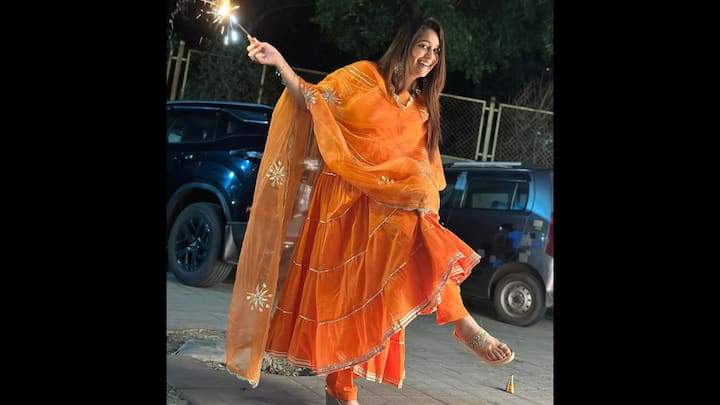 3. Vibrant Orange Anarkali Suit: Dipika Kakar channels festive cheer in this radiant orange Anarkali suit, glowing like a sparkler herself. The flared silhouette brings drama and movement, while the zari-lined dupatta with floral gota patti embroidery adds the perfect traditional flourish. This joyful and vibrant sunset orange look is unapologetically desi and rooted in tradition. The layered kalis and mirror detailing catch the light effortlessly. This look is your go-to if you want to stand out without compromising on comfort and culture. (Image Source: Instagram/@ms.dipika)