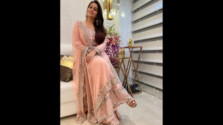 2. Ethereal Pastel Pink Set: Dipika Kakar exudes grace in this pastel peach sharara set featuring intricate mirror work and delicate silver embroidery. The flowy, sheer dupatta adds a dreamy layer, while the tailored kurta and matching sharara pants bring comfort and elegance together. The reflective embellishments along the borders catch the light beautifully, perfect for both indoor poojas and Instagram-worthy photo ops. This look is a beautiful pick for people who want to embrace tradition with a touch of sparkle. (Image Source: Instagram/@ms.dipika)