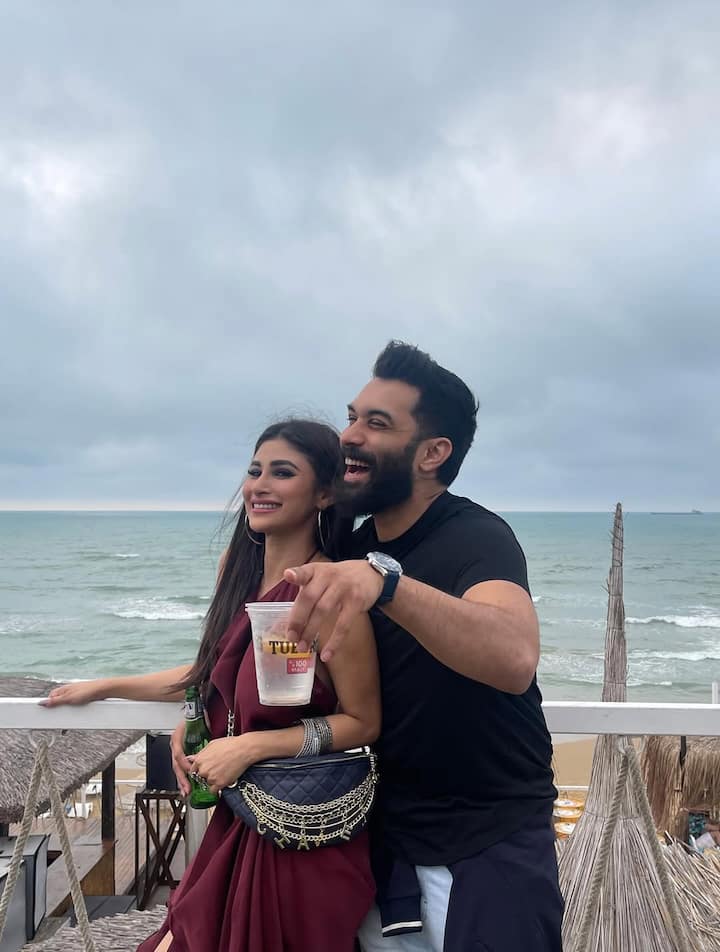 Mouni Roy & Suraj Nambiar’s Birthday Photo Dump Is Straight Out Of A Romance Film, See Pics Another photo shows Mouni in a maroon sleeveless dress with a chain belt bag, laughing with Suraj at a beachside café.