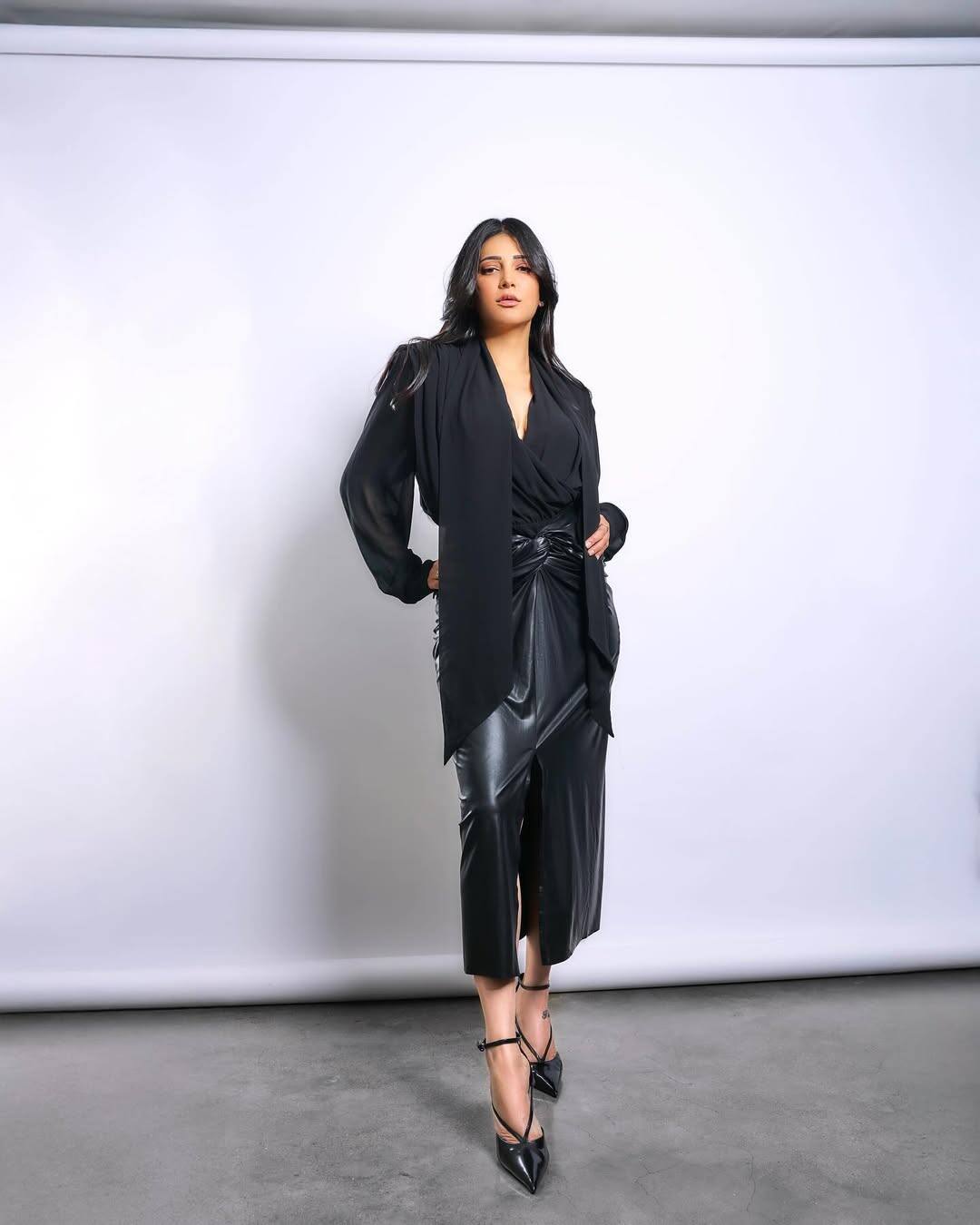 The actress is wearing a black puffy sleeves top and a middle length leather skirt in this look. To complete this look, he is wearing a tie up heel.