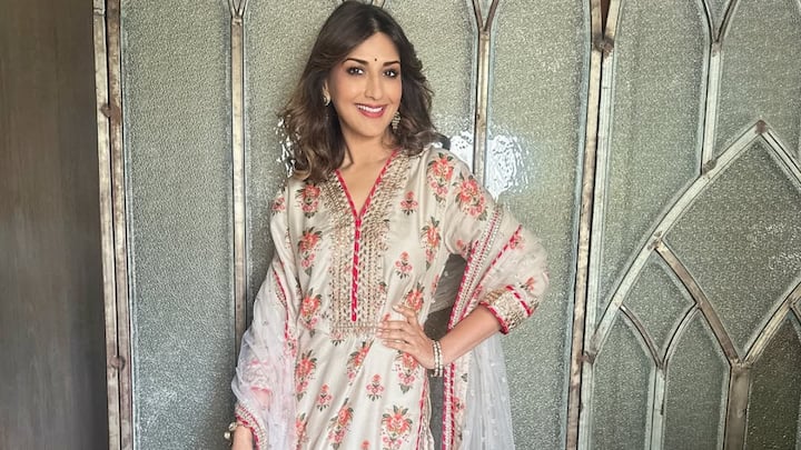 In this white floral suit with intricate border embroidery, Sonali paired a sequined dupatta with a voluminous sharara. This ensemble brings charm and femininity to festive dressing. (Image Source: Instagram/ iamsonalibendre)