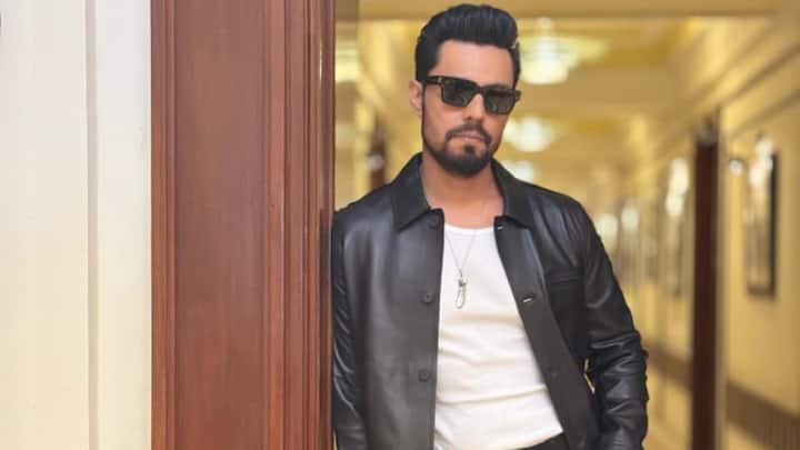 The Leather Luxe Look: A black leather jacket thrown casually over a white tee with fitted black denims, this classic pairing gets elevated by his confident stance and dark sunglasses. Effortless, sharp, and undeniably masculine. (Image Source: Special Arrangement)