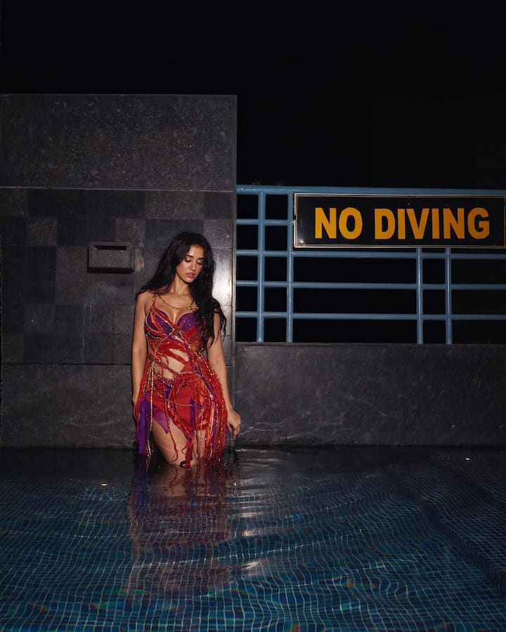 In this look, Disha is wearing a cut-out dress with red and purple shades on poolside, which has a design of fringes and string. Wet dress and wet hair are making this picture more sizzling.