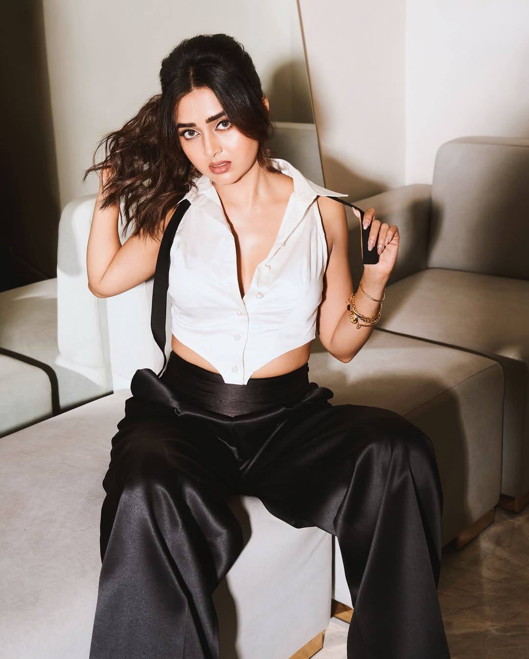 In this look, Tejashwi is wearing black wide pants with white color deep neck short shirt, giving them a classy touch. Open hair, light wavy hairstyle, nude makeup, sharp eyeliner, lipstick of light shade and golden bracelet in hands are making the entire look perfect combination of both glamorous and elegant.