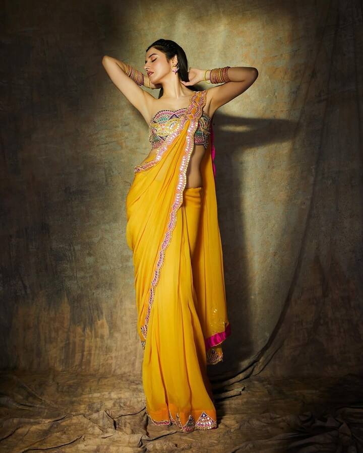 This Imbodard saree of Yellow color has been styled by Divya with off shoulder blouse. Multicolor jewelery is adding to his look.