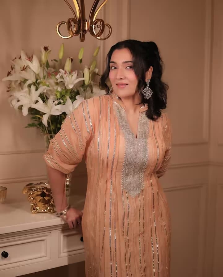 टीना आहूजा पीच रंग के एथनिक आउटफिट में बेहद खूबसूरत लग रही हैं। सिल्वर वर्क वाली यह ड्रेस उनके पूरे लुक को रॉयल टच दे रही है। लंबे ईयररिंग्स और नेचुरल मेकअप उनके एथनिक स्टाइल को पूरी तरह से कॉम्प्लीमेंट कर रहे हैं। खुले बालों के साथ टीना का ट्रेडिशनल स्टाइल बेहद एलिगेंट और आकर्षक है।