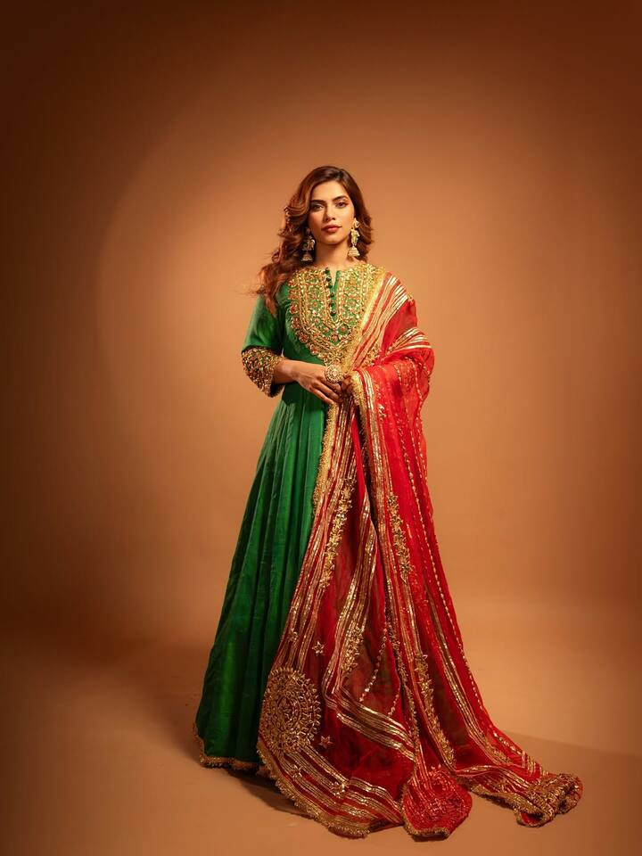 In this royal look, Nagma is wearing dark green ethnic gown-style outfits, which is embroidered with beautiful golden threads. With this, he has carried a red colored heavy border scarf, on which the Golden Embroidery and the design is giving a beautiful touch to this entire look. Hair, statement earrings and satal makeup with open light curls are completing this look perfectly.