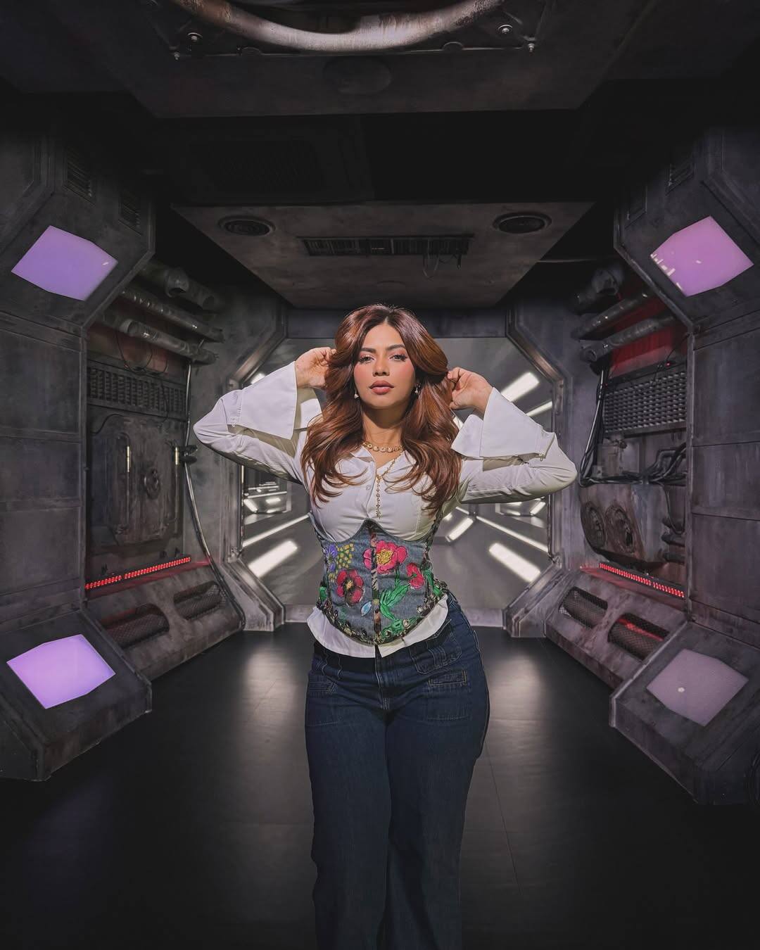 In this look, Nagma is wearing a white colored bell-sleeve top, which is paired with a corset belt with colorful flowers, giving a touch in her look. He has pair this outfit with dark blue jeans. Open and light waves, light makeup and nude lipstick are completing her look.