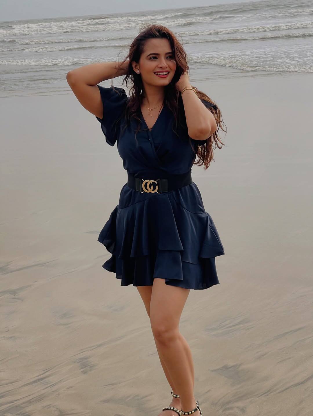 In this look, Neelam is wearing a navy blue short frill dress, which is styled with a black belt on the waist. Open hair, light makeup and red lipstick are completing this glamorous look.