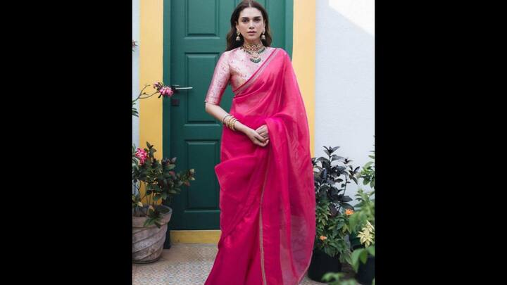 2. Aditi Rao Hydari: If you’re looking for a bold yet graceful festive look, take inspiration from Aditi Rao Hydari’s stunning hot pink organza saree. The sheer drape with a delicate gold border makes a striking festive statement. The vibrancy of the pink hue brings in just the right dose of celebration for Ganesh Chaturthi 2025. Aditi chose a high-neck silk brocade in soft pastel pink with intricate detailing that elevated her fit. Paired with a traditional choker, layered jewellery, and jhumkas, her ensemble radiates old-world charm with modern minimalism. (Image Source: Pinterest/carnival_store_)