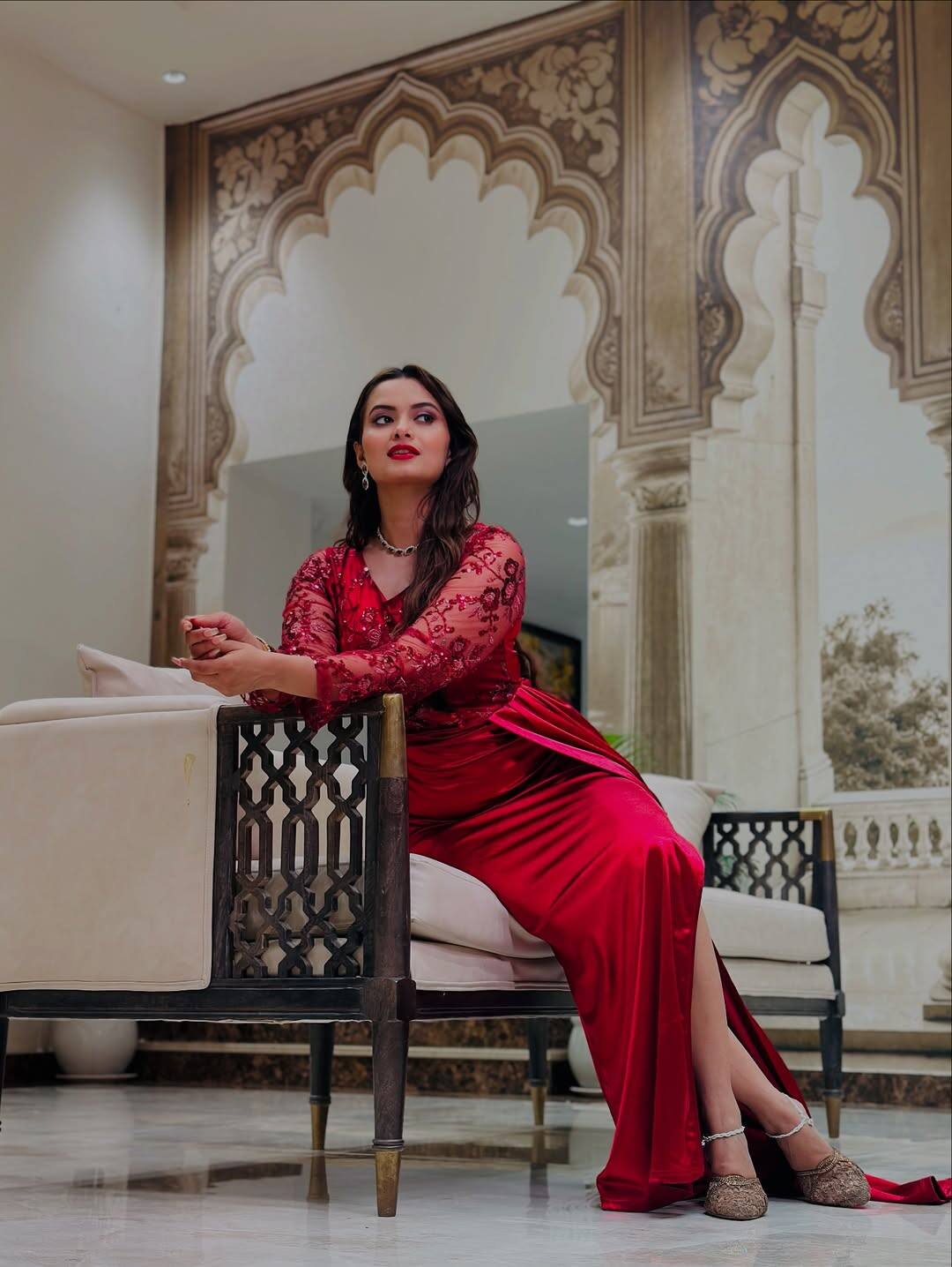 In this look, Neelam is wearing a bright red colored gown which has a full sleeve top of the net laces and a satin finish skirt. The gown also has a high slit. Red lipstick, light makeup and open hair are completing their look.