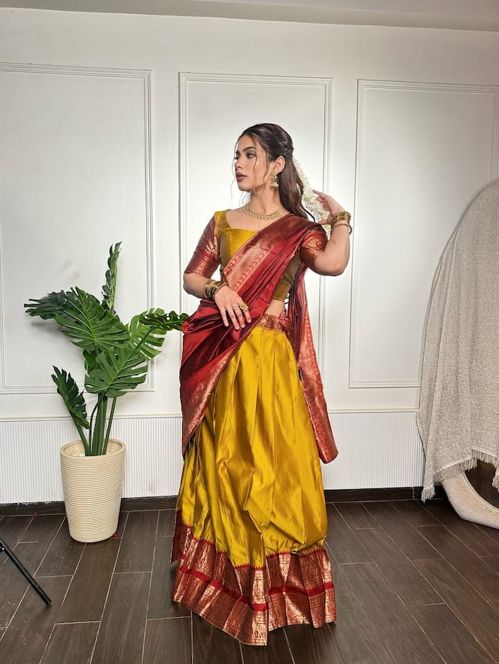 In this look, Nagma is wearing a yellow rich silk lehenga, which is decorated with maroon and golden border. With this, matching blouse and maroon silk scarf are making their entire look royal. Open hair, gold jewelery and bangles in their hands are completing their traditional style.