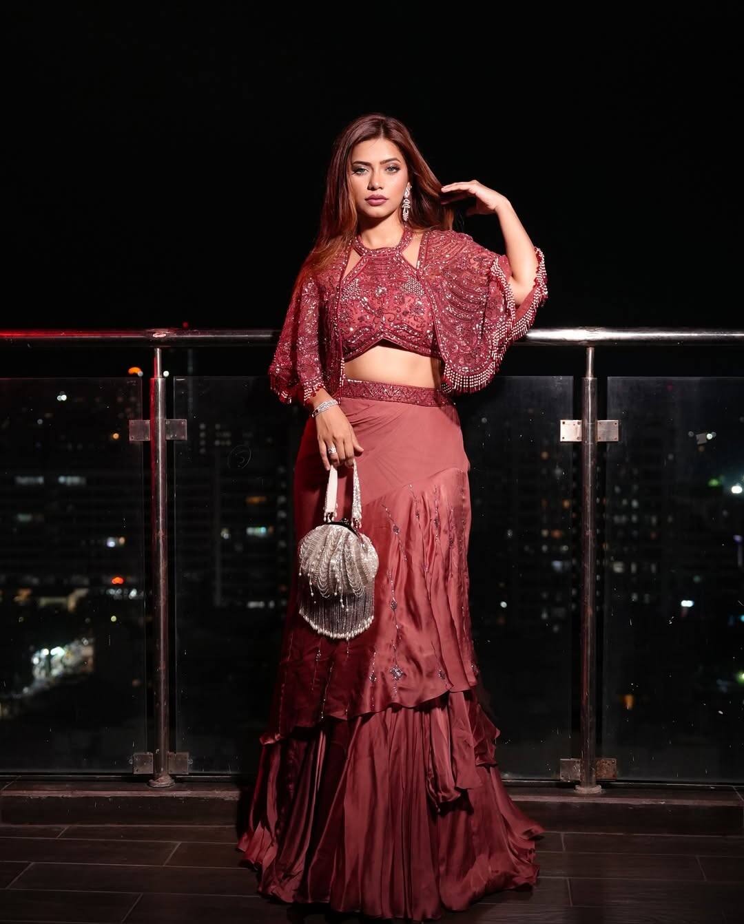 In this picture, Nagma Mirajkar is wearing a shimari outfit of wine red color. There are sequin work and flared sleeves on the blouse, making the look more stylish. He has taken a stylish bag of silver color, which is giving modern touch in their traditional look.