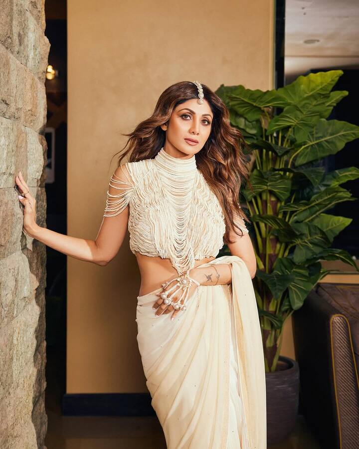 Shilpa has carried an all-off-white look in this picture. She is wearing a heavy and modern design blouse with off-white saree, which has a detailed fringe style. Traditional demand vaccine, hand -worn statement jewelery piece, open wavy hair and nude makeup are giving their look a modern and traditional vibe.
