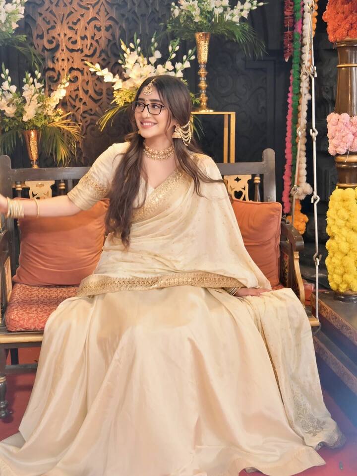 Shivangi's look in this look is very traditional. He is wearing an off-white colored lehenga-choli and scarf, which has a golden border and light embroidery detailing. Long open hair and demand on the forehead, heavy jewelery in the ears and the necklace around the neck are completing their traditional look. He has completed his Indian look wearing bangles. Wearing light makeup and glasses on the face, Shivangi has also added a cute modern touch to this traditional avatar.