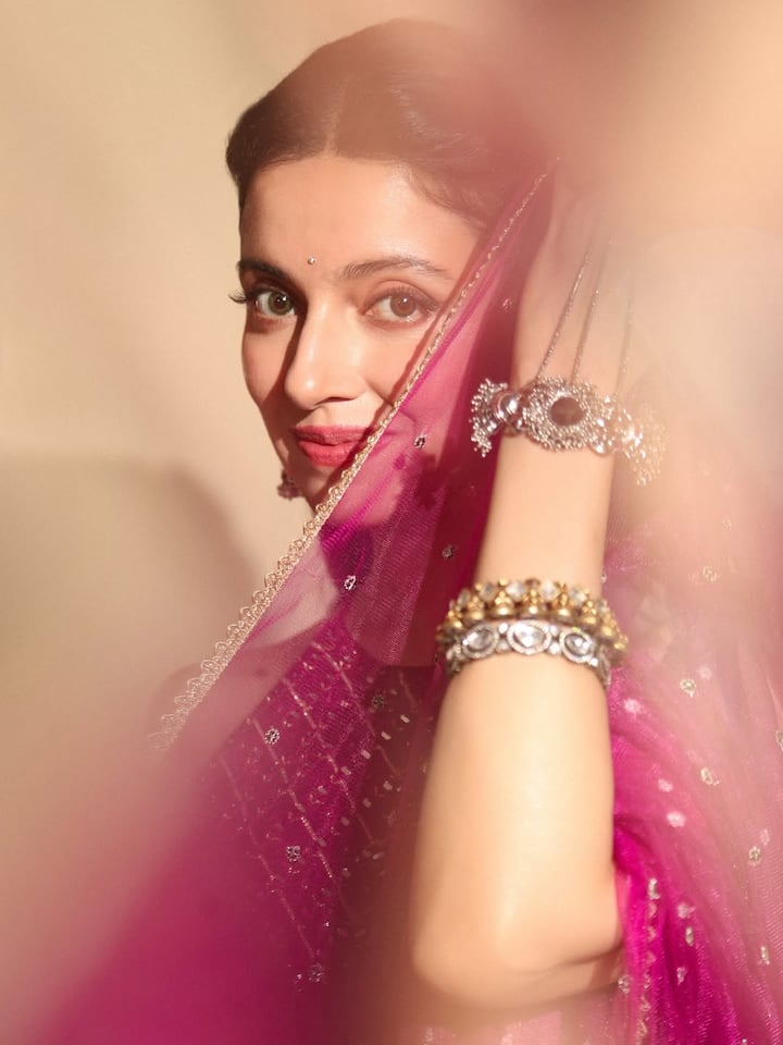 Paired with a sleeveless embellished blouse, the outfit strikes a perfect balance between festive glamour and contemporary style. The sheer dupatta with dainty golden butis further enhances the ensemble, giving it a flowy and ethereal appeal.