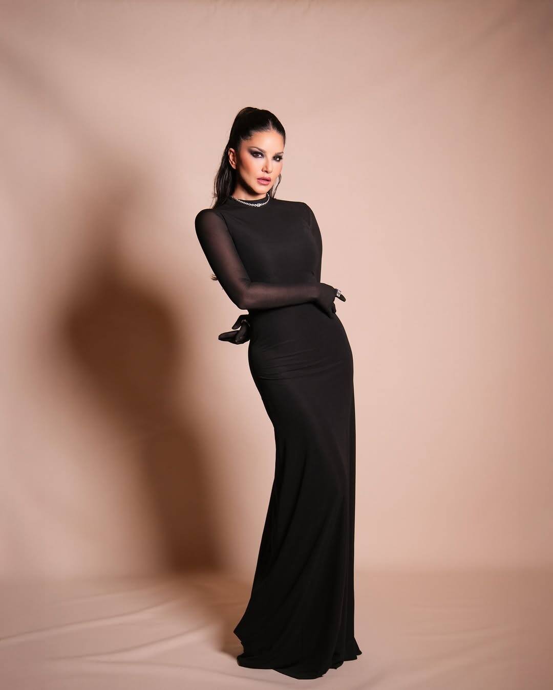 Sunny looks very elegant and classy in this outfit. She is wearing a black body-fitted gown, which is styled with high ponytail and minimal jewelery. His pose and expression is making this look even more AG.