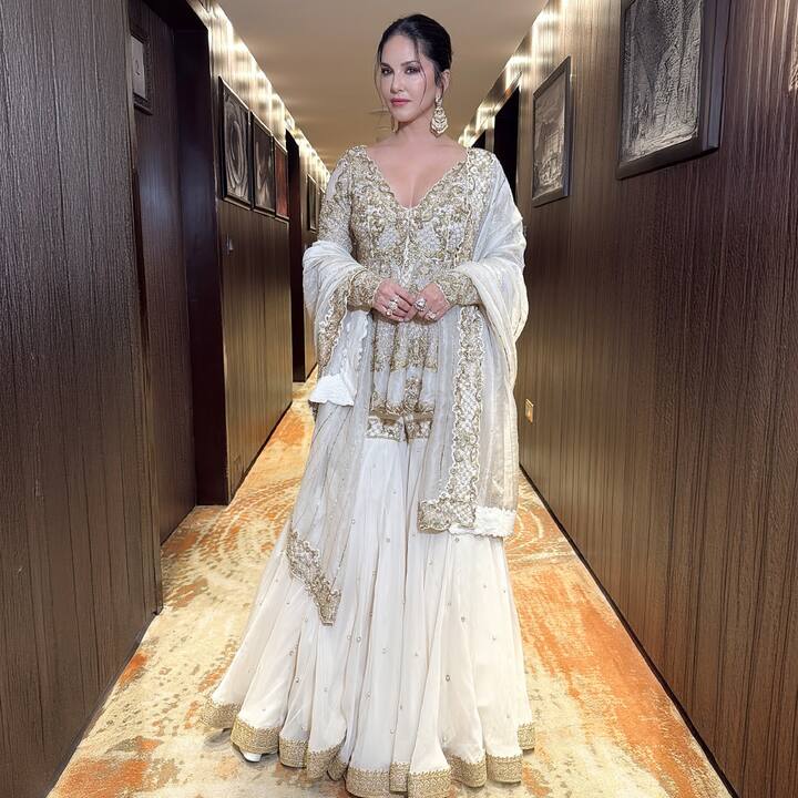 इस लुक में सनी ने व्हाइट और गोल्डन रंग का हैवी एम्ब्रॉइडरी वाला डीप नेक लहंगा पहना है. इस लुक को पूरा करने के लिए उन्होंने बड़े इयरिंग कैरी किया है. इस लुक को उन्होंने मेस्सी बन हेयरस्टाइल बनाया है.