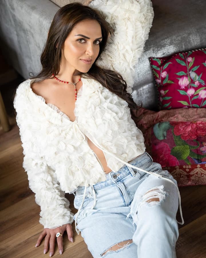 In this picture, Isha has a casual look. He is wearing a ripped denim jeans with a white texcharged top. Open hair, natural makeup and red jewelery of red beads around the neck are adding their entire look.