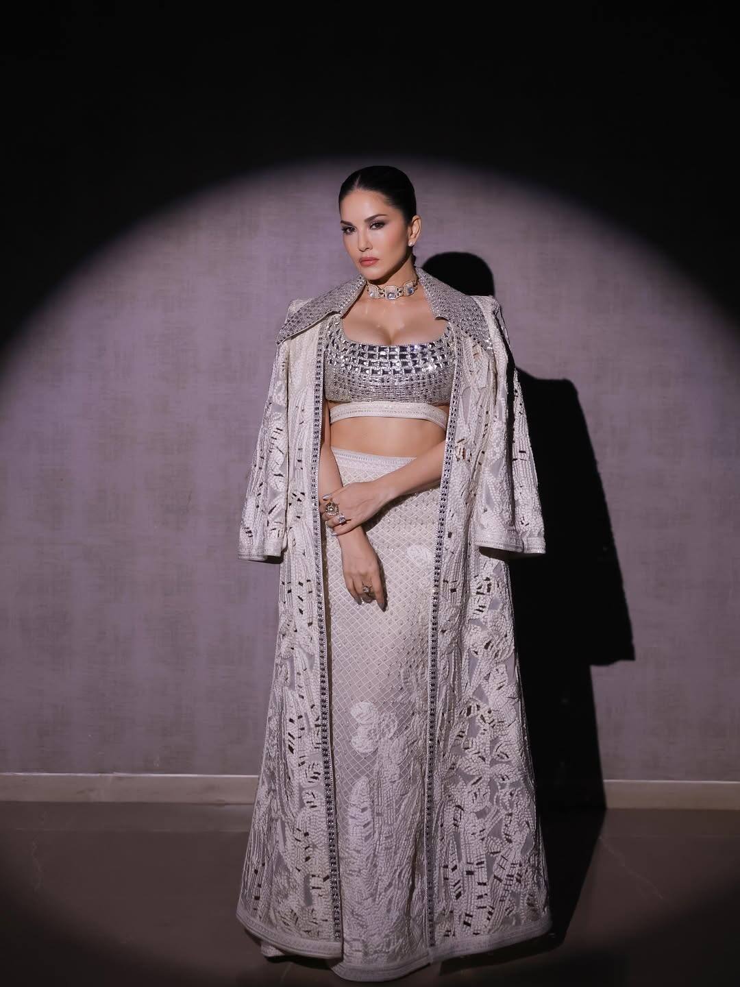 In this look, Sunny is wearing a heavy embroidery outfit of silver and white combination, which has shimmery blouse and long jackets. His look with sleek hairstyle and minimal jewelery is giving a completely different vibe.
