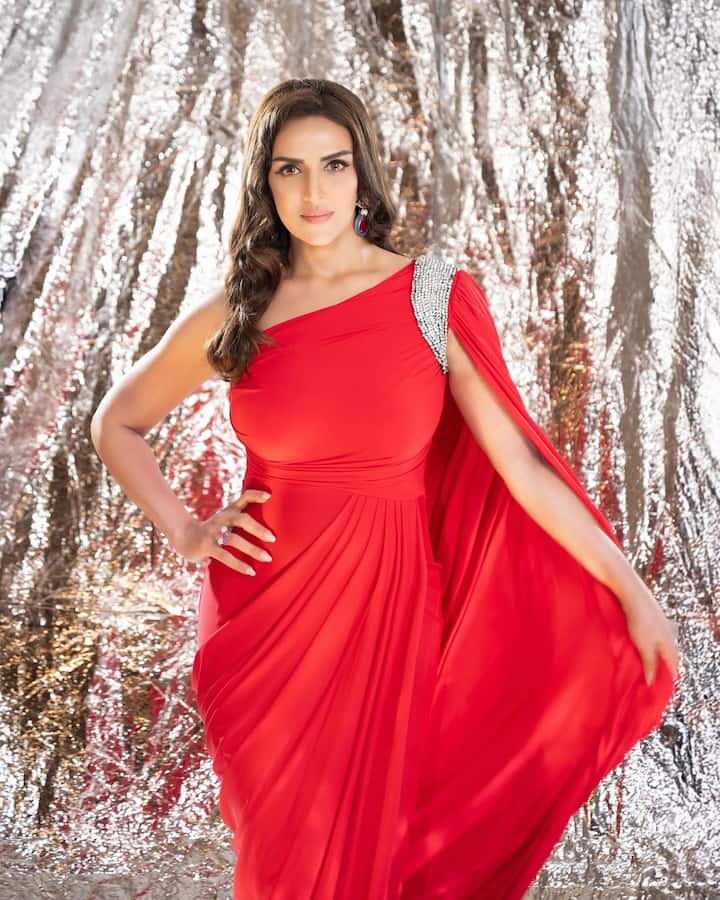 In this look, Isha has carried a red off-shoulder gown, on whose shoulder the silver embellishment detailing is giving her outfit and Royal Touch. Floi fabric and drape styling is making them look more special. Nude makeup, shiny earrings and Satal hairstyles are balanced by her look.