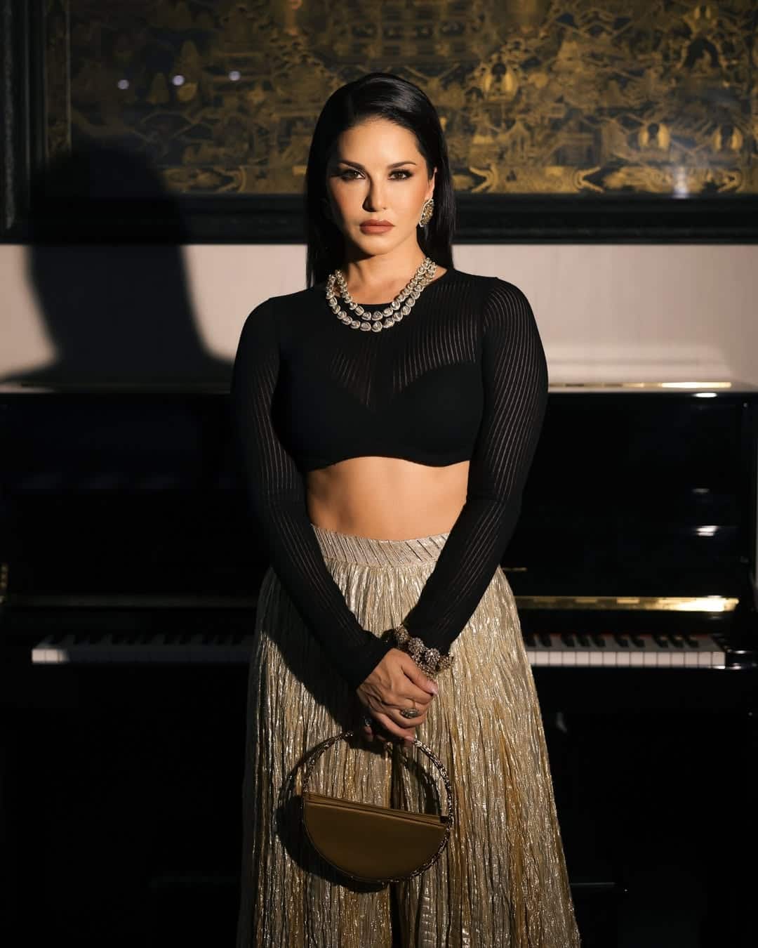 In this glamorous and elegant look, Sunny has pairing the Black Full Sleeve Crop Top with a golden shimari lehenga. The statement is complementing his look, large earrings and a stylish golden bag. Simple straight hair and nude makeup are completing their entire look.