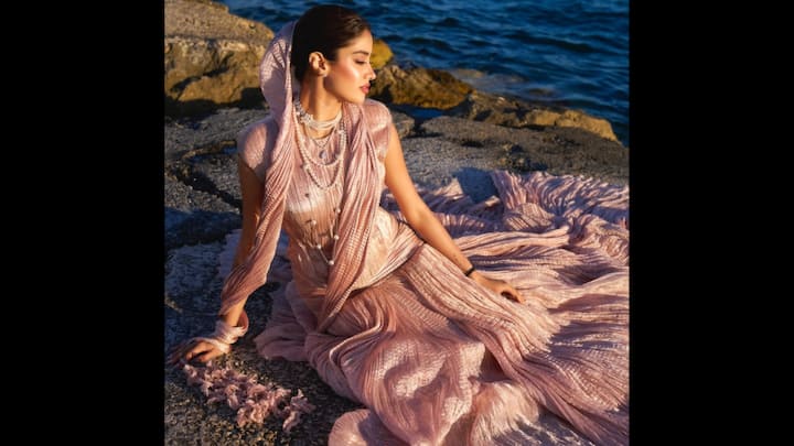 3. Janhvi Kapoor: At the 78th Cannes Film Festival, Janhvi Kapoor turned heads in a breathtaking rose-gold pleated lehenga set that redefined contemporary ethnic wear. The outfit featured a structured blouse with a fluid, metallic pleated skirt, styled with a scarf-style dupatta draped. Instead of going for heavy jewels, Janhvi layered pearls in multiple strands, adding an old-world charm to her futuristic ethnic fit. (Image Source: Instagram/@janhvikapoor)