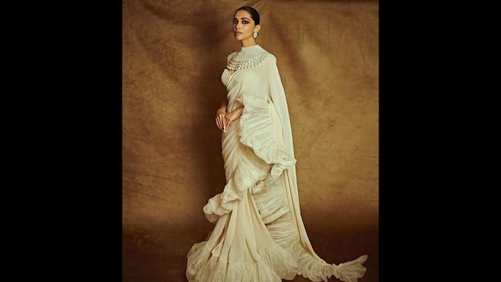 6. Deepika Padukone: Deepika Padukone: The ivory ruffled saree worn by Deepika Padukone, is a masterclass in contemporary ethnic styling. This saree reimagines the classic drape with layered pleated ruffles that add movement and a modern edge to the timeless silhouette. Instead of heavy embroidery, the statement lies in its structural detailing and bold textures. Deepika elevated the look with a dramatic multi-layered pearl collar accessory and statement studs. (Image Source: Instagram/@deepikapadukone)