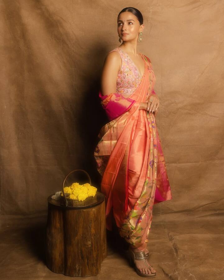 इस लुक में आलिया ने पीच-ऑरेंज शेड की पायठणी स्टाइल साड़ी पहनी है, जिसे उन्होंने मराठी स्टाइल मे ड्रेप किया है. मैचिंग एम्ब्रॉयडर्ड ब्लाउज़ और हल्की जूलरी उनके लुक को बैलेंस कर रही है. सिंपल हेयरस्टाइल और मिनिमल मेकअप उनकी नैचुरल ब्यूटी को एनहान्स कर रहा हैं.