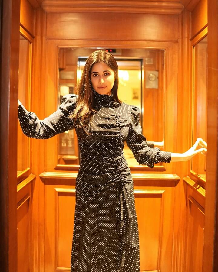 In this look, Katrina is wearing a black polka dot dress, which has high neck and puff sleeves. The fitted pattern of the dress and draping on the side. Open hair and his look without more accessories is very stylish and classy.