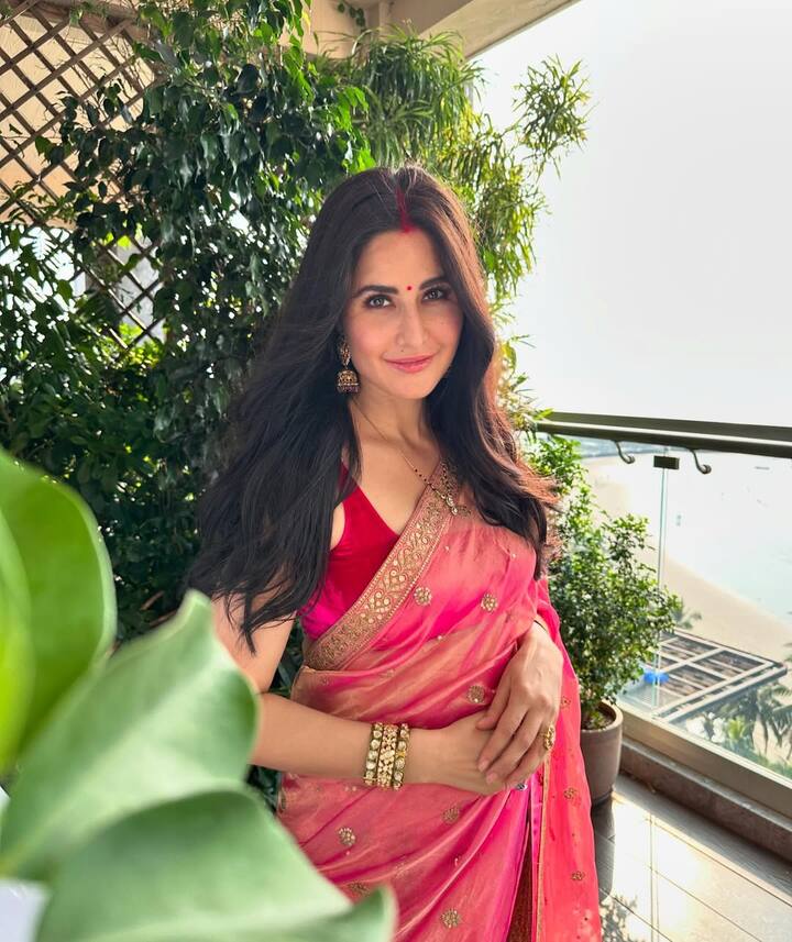 Katrina is wearing a red blouse with a pink saree in this picture, which has been made a golden border and small boots. Open hair, vermilion on the forehead, red bindi and gold jewelery are giving traditional touch to their look.