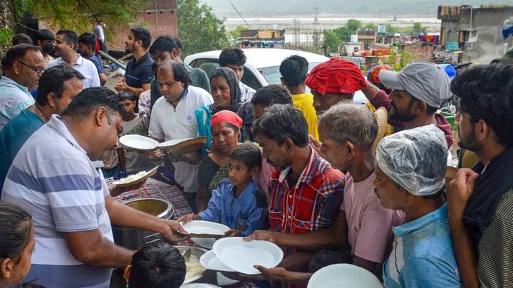 Flood-affected people collect food at camp, near the swollen Tawi river, in Jammu. (Image Source: PTI Images)