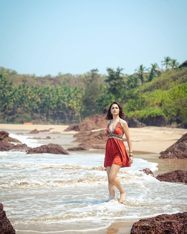 In this look, Anit is wearing an orange short dress which is perfect for beach vibes. Open hair and natural makeup are completing their look. His look looks quite fresh while walking on the beach.