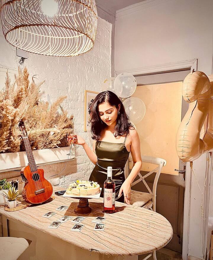 This look of Anit is giving a very party vibe. She is wearing an olive green silky dress which is making her sophisticated. Light makeup and open hair are giving even more graceful touch to their entire look. Cakes, wine and decorations on the table are making their look perfect with a celebration mood.