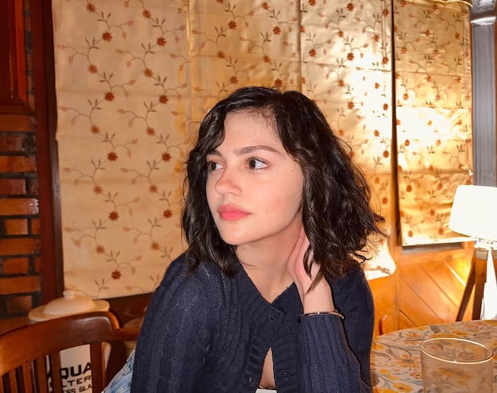 Anit is giving a soft girl look in this picture. He is wearing a navy blue sweater. Light makeup and open curly hair are further enhancing the innocence of their face. The war -like warm atmosphere is visible in this look.