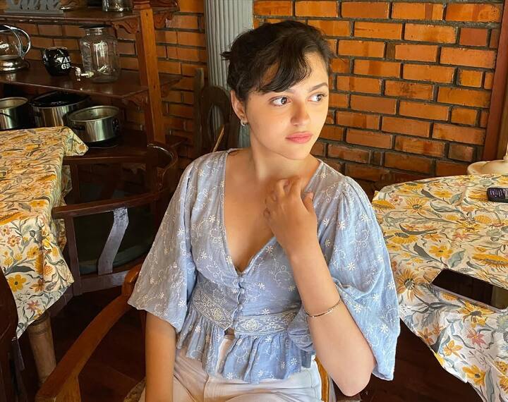 In this look, Anit is wearing a light blue floral top, which has a bell sleeves and button detailing, giving them a cute vibe. Light makeup and tied hair are highlighting the natural beauty of their face.