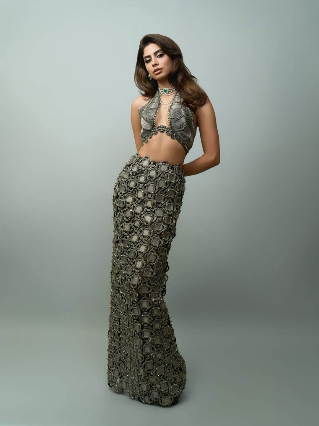 This look of happiness is very experimental and high-fashion style. He is wearing a heavy detailed co-ord set with metallic tone, with a unique pattern skirt and matching bold cut top. Green stone statement neckpiece and layered pearl jewelery is making his look even more royal and elegant.