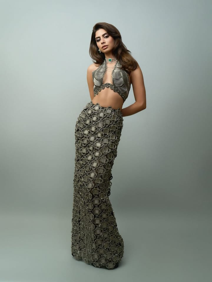 This look of happiness is very experimental and high-fashion style. He is wearing a heavy detailed co-ord set with metallic tone, with a unique pattern skirt and matching bold cut top. Green stone statement neckpiece and layered pearl jewelery is making his look even more royal and elegant.