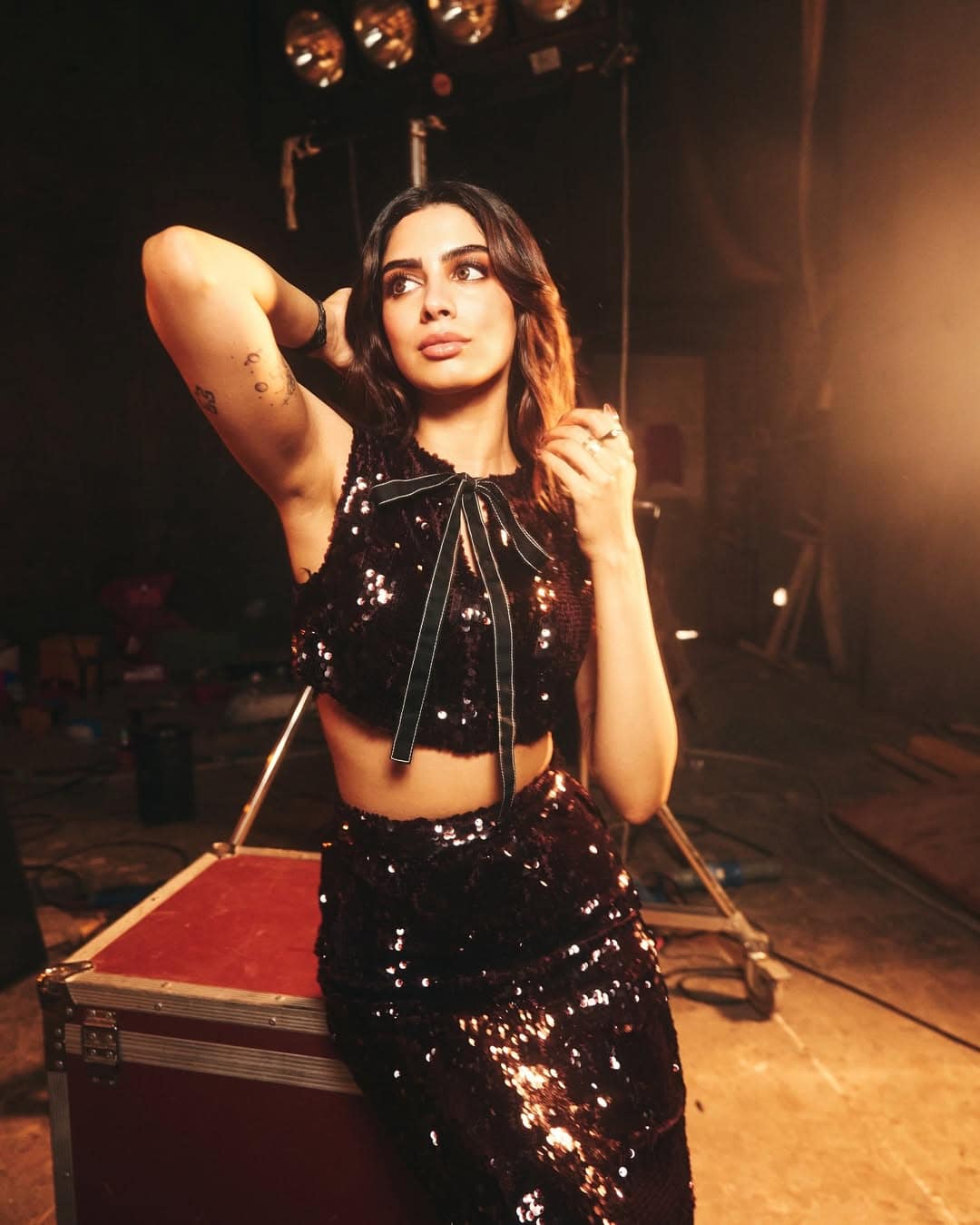 For this party vibes look, Khushi is wearing a black sequin co-ord set with a sleeveless crop top and matching skirt. Bo detailing at the top is making his look cute but glamorous. Open wavy hair and nude makeup are giving more sharp touch to this entire style.