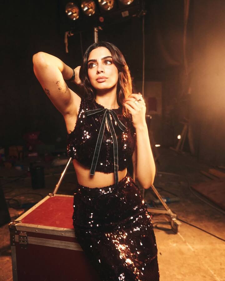 For this party vibes look, Khushi is wearing a black sequin co-ord set with a sleeveless crop top and matching skirt. Bo detailing at the top is making his look cute but glamorous. Open wavy hair and nude makeup are giving more sharp touch to this entire style.
