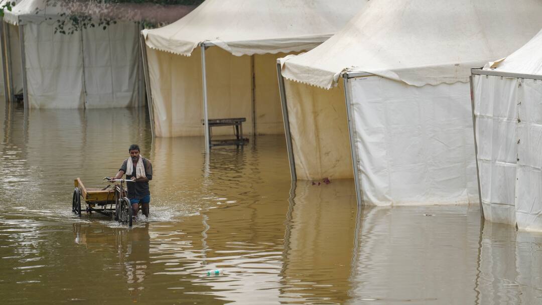 दिल्ली के कई इलाकों में बाढ़ का खतरा बरकरार, खतरे के निशान से ऊपर बह रही यमुना; बीमारियों का खतरा भी बढ़ा delhi flood update yamuna water level drops many areas still submerged disease risk in relief camps दिल्ली के कई इलाकों में बाढ़ का खतरा बरकरार, खतरे के निशान से ऊपर बह रही यमुना; बीमारियों का खतरा भी बढ़ा