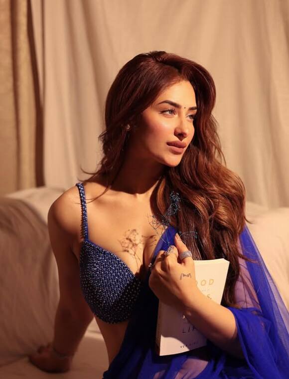 The actress wearing a bright blouse with a blue color Georgette saree is looking amazing. The dot on the forehead is increasing her beauty.